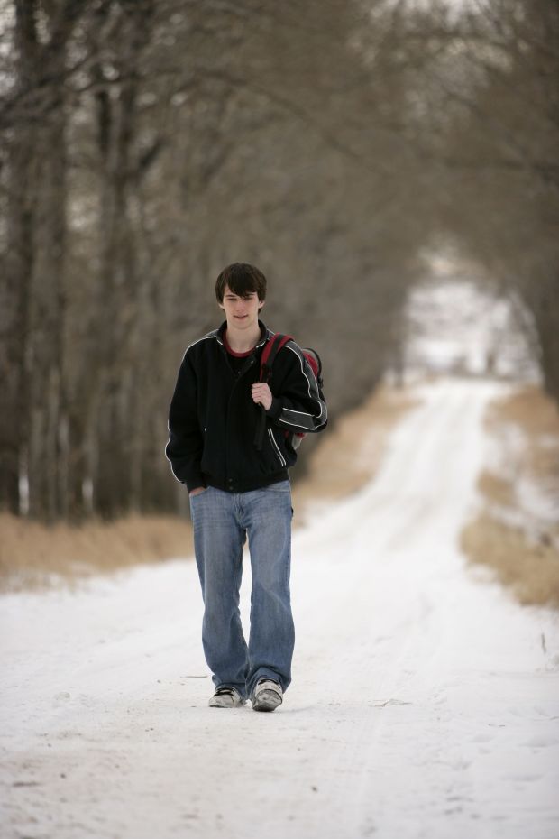 Young man walking up a snowy road
